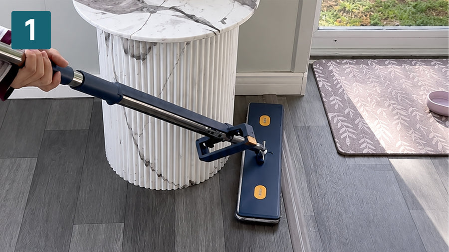 360-degree swivel head steering the flat mop around a table base on grey timber flooring