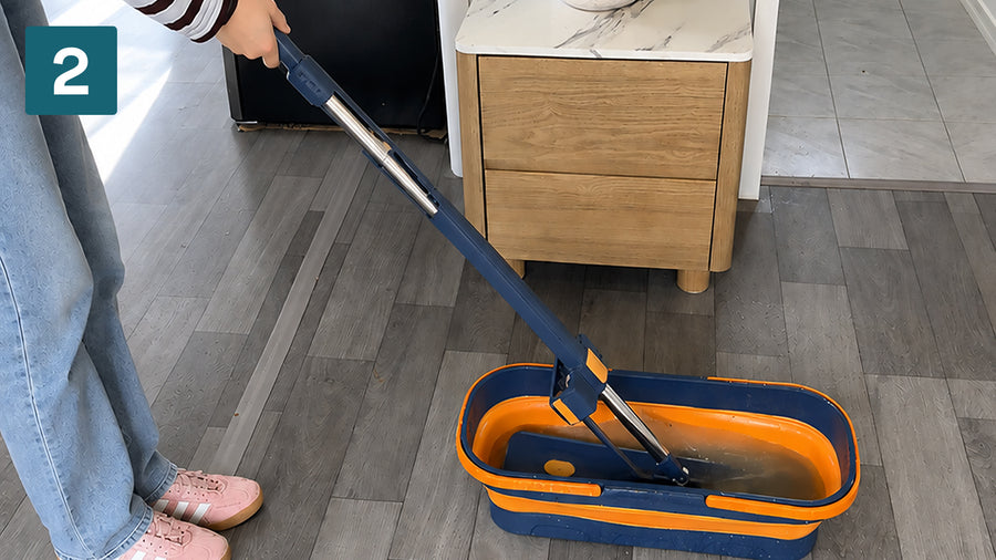 Rinsing the flat mop pad in the bucket rinse chamber on a timber-look floor