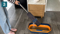 Wringing the microfibre mop pad dry over the bucket scrapers without touching the water
